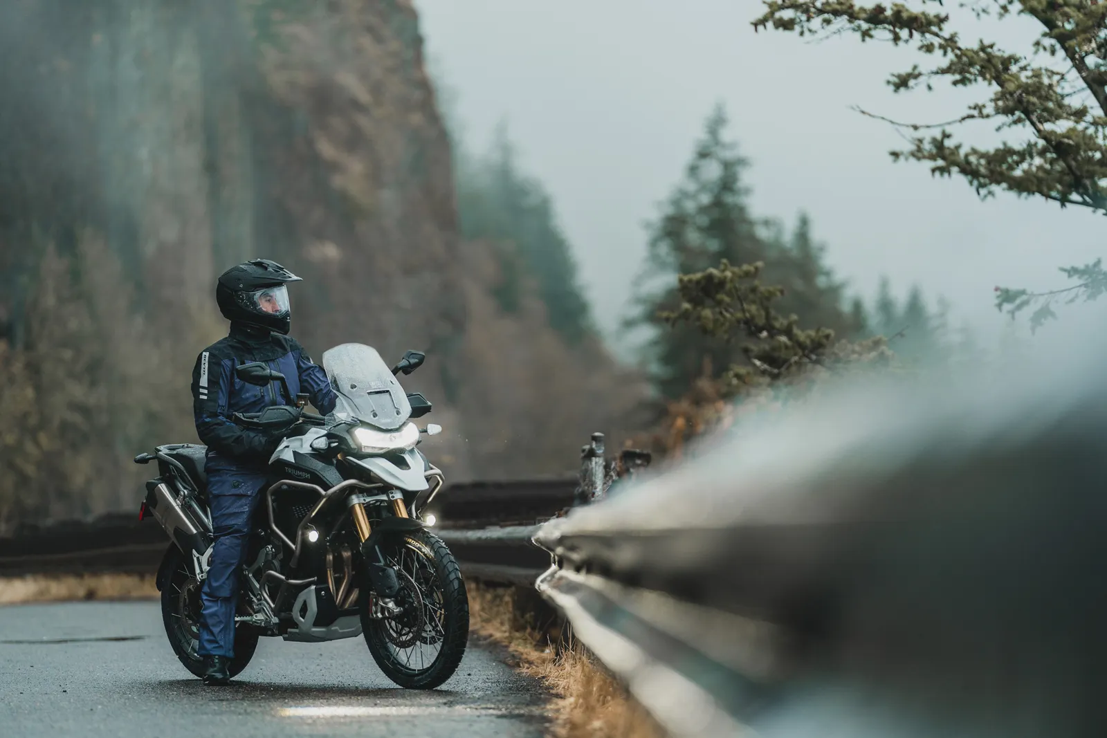 Motociclist oprit lângă motocicletă pe drum de munte