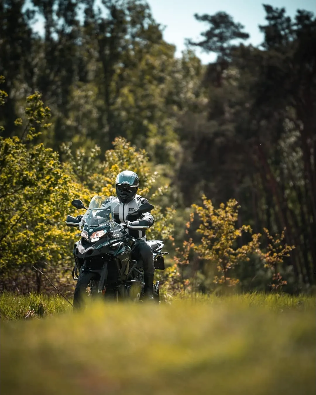 Motociclist în geacă de vară pe drum forestier