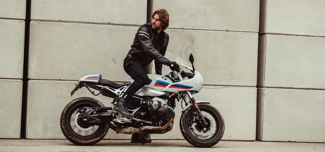 Cadru real cu rider purtând blugi REVIT Jackson 2 SK pe motocicletă, cu fundal urban și motocicletă întreagă în imagine