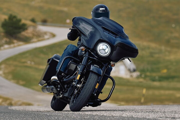 Motocicletă touring pe drum virajat, cu anvelopa față încărcată în viraj